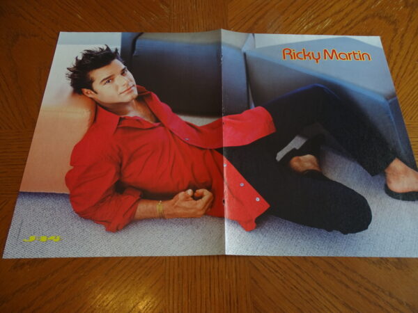 Ricky Martin laying down Menudo red shirt